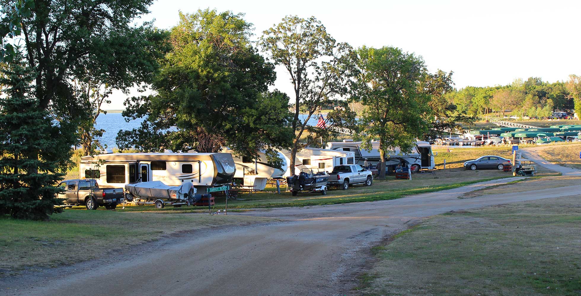 A line of RV’s and cars parked on a sunny day for camping at Eastbay Campground with close access to the lake and marina.