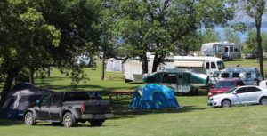Tents, RV’s and cars parked on and around the grassy sites for tent camping at Eastbay Campground.