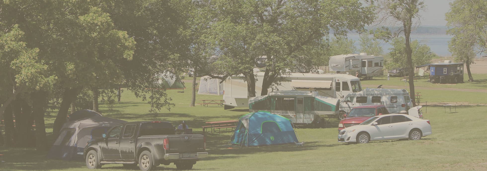 Tents, RV’s and cars parked on and around the grassy sites for tent camping at Eastbay Campground.