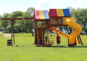 A few kids play on a colorful wooden playground at Eastbay Campground.