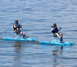 Two people in individual water bikes with life vests enjoying a sunny day on the lake at Eastbay Campground.